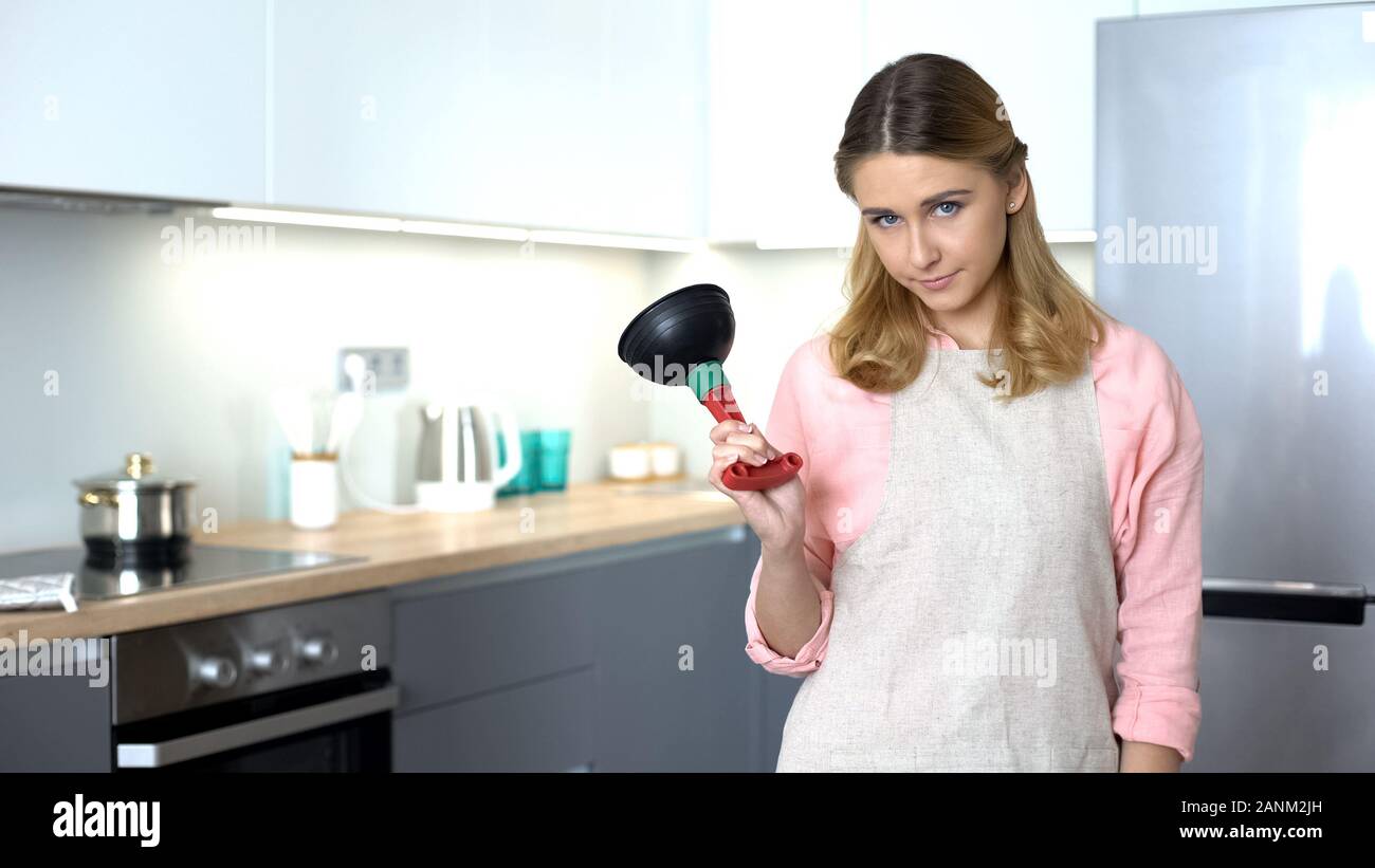 Dissatisfied housekeeper showing plunger, tool to unclog drain, plumber service Stock Photo