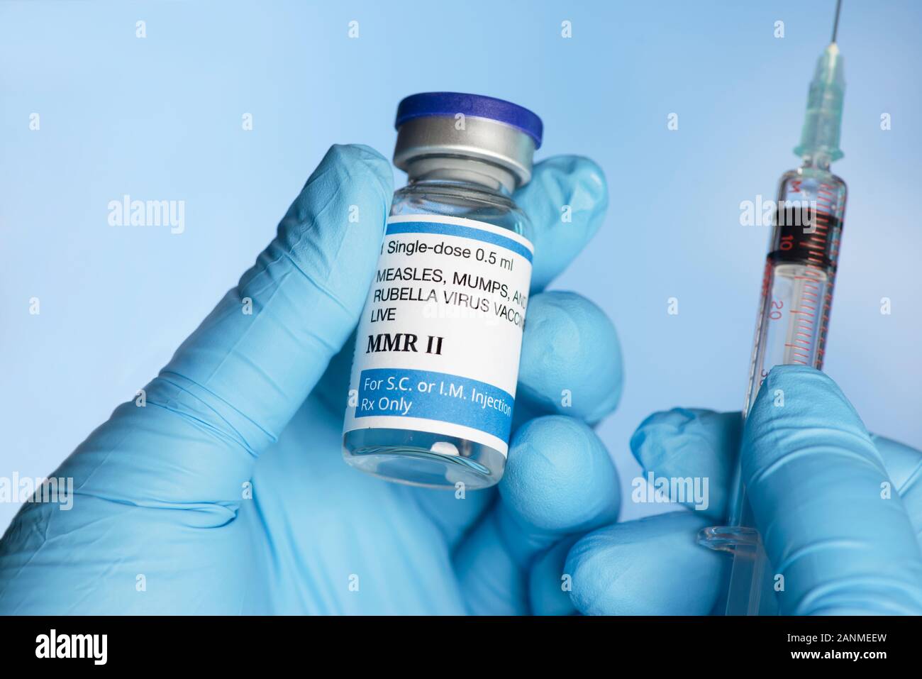 Nurse holds MMR 2 -measles, mumps, rubella vaccine vial in gloved hand with syringe. Stock Photo
