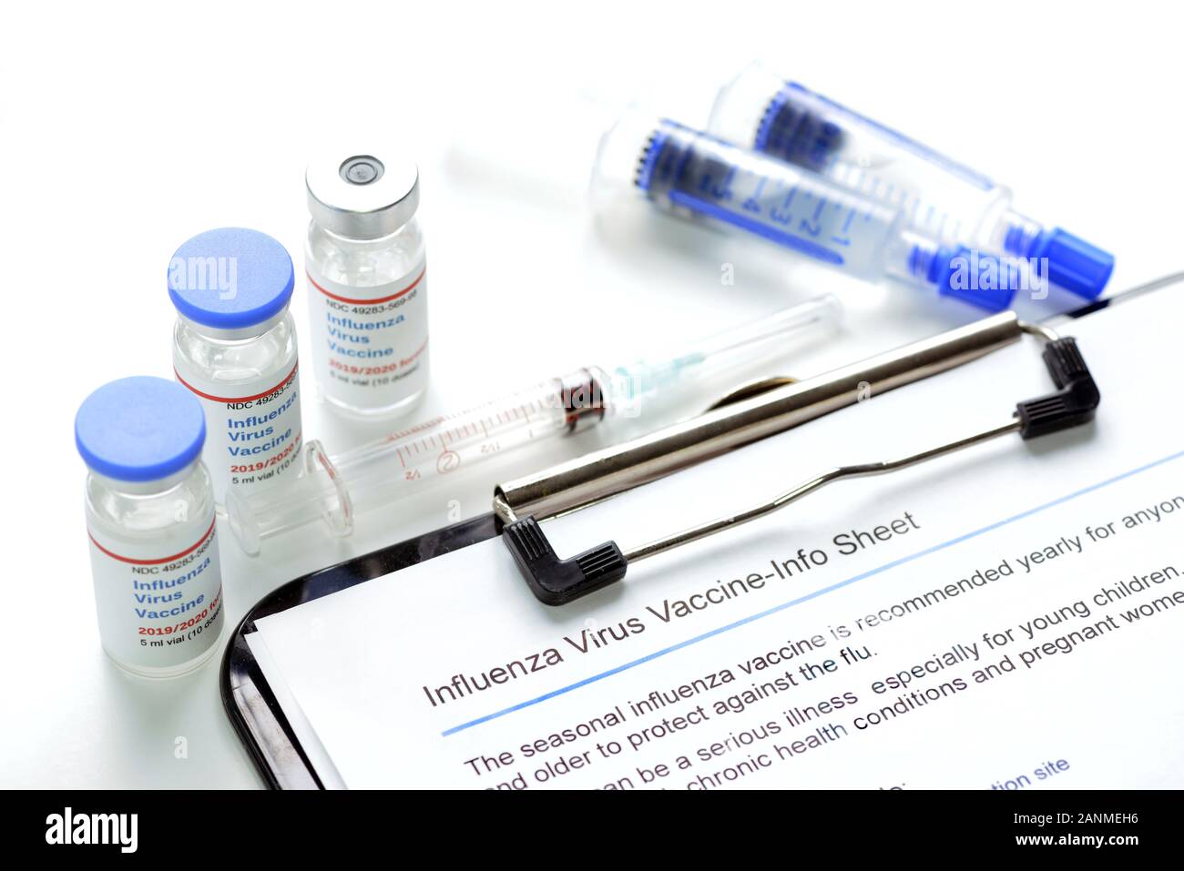 2019/2020 Influenza virus flu shot vaccine vials and syringe with flu shot information sheet on clipboard. Stock Photo