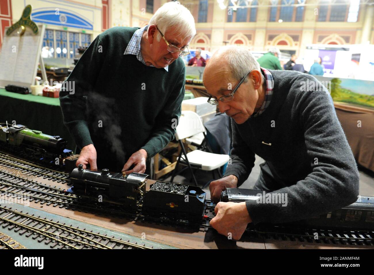 Enthusiasts preparing a 16mm narrow gauge train at the London Model Engineering Exhibition which opened today at Alexandra Palace, London.  The show is one of the largest modelling exhibitions in the UK, blending the full spectrum of model creation from traditional model engineering, steam locomotives and traction engines through to more modern gadgets and ‘boys toys’ including trucks, boats, aeroplanes and helicopters.  Over 45 national and regional modelling clubs and societies and associations will be displaying their member’s work and competing to win the prestigious Society Shield. In tot Stock Photo