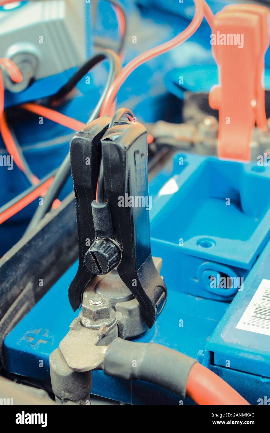 Car battery charging under hood of car. Charger with connected cables