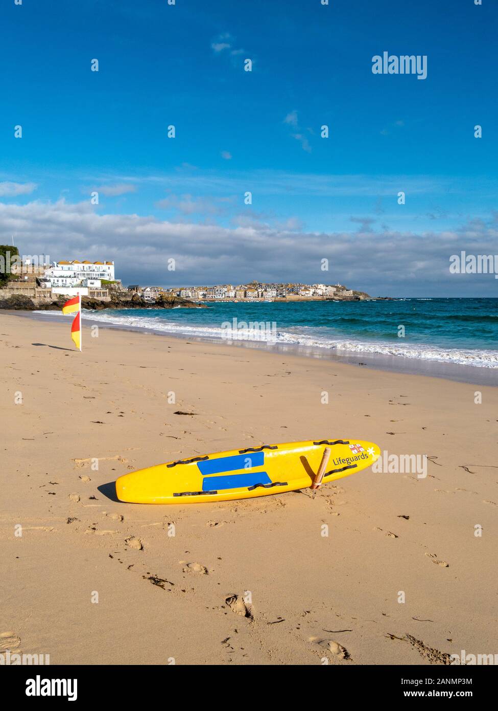 Lifeguard's yellow paddle / surf / rescue board on Porthminster beach in late summer, St Ives, Cornwall, England, UK Stock Photo