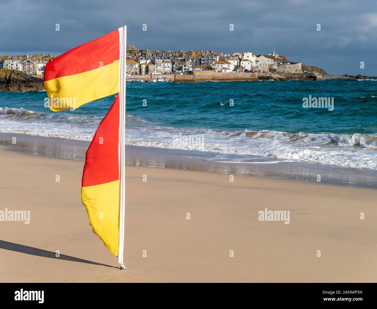Lifeguard flags blowing in sea breeze marking safe swimming area, Porthminster Beach, St Ives, Cornwall, England, UK. Stock Photo