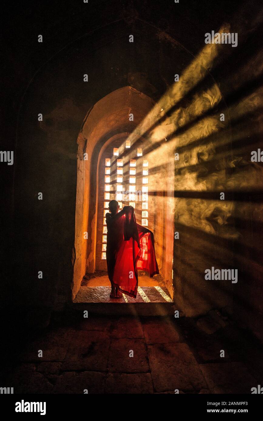 Sunset rays catches a monk praying in a buddha temple in myanmar Stock Photo