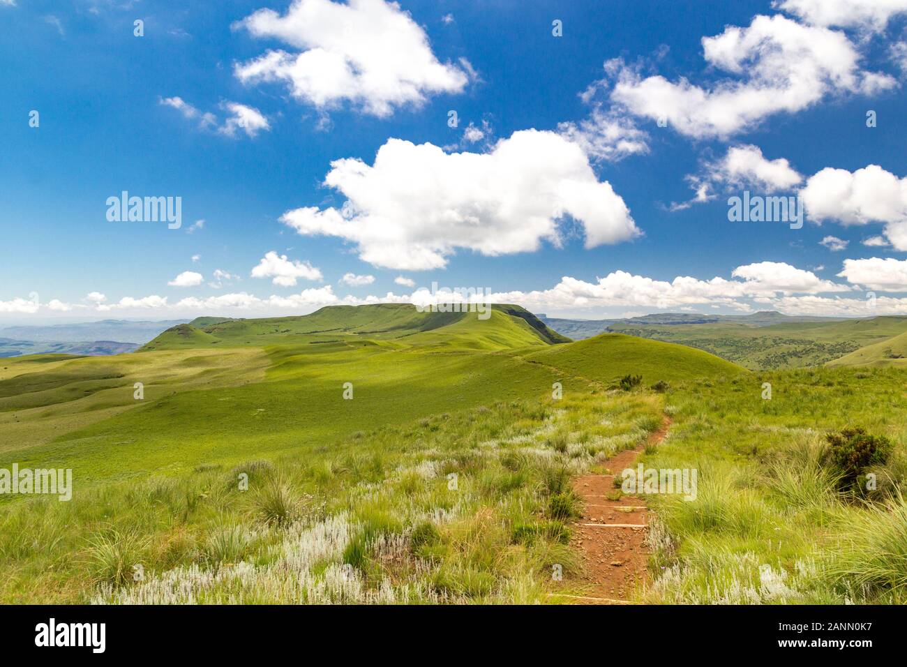 Panoramic view from a grassy plateau with a small hiking trail to soft green mountains, Giants Castle Game Reserve, Drakensberg, South Africa Stock Photo