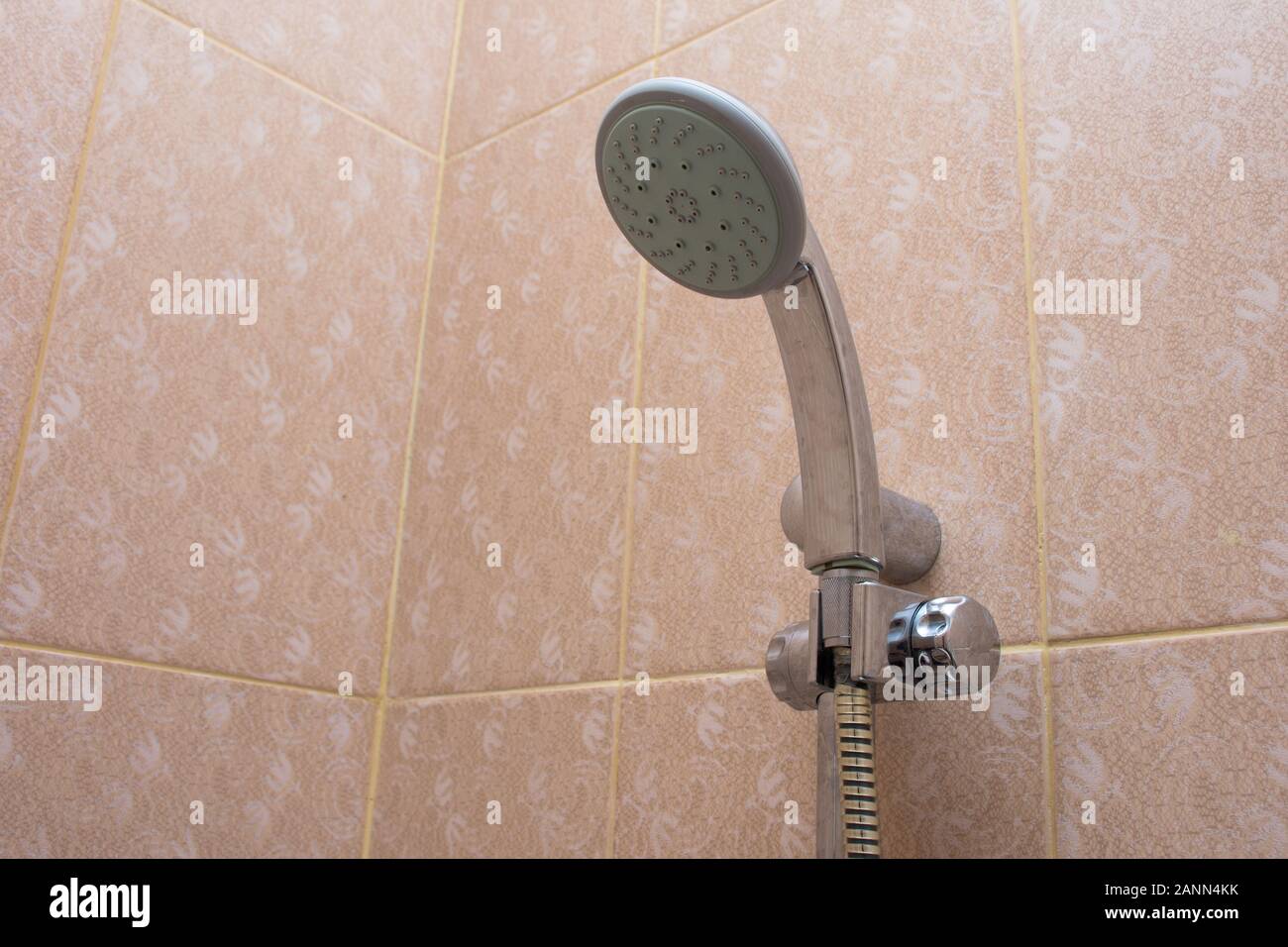 Rain shower head in the bathroom handing on orange tile for cleaning
