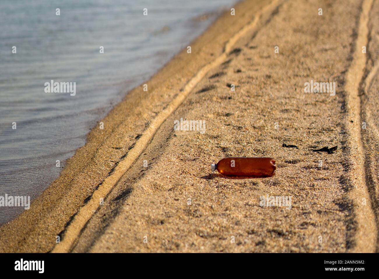 Empty plastic bottle lying on the sandy beach. Environmental pollution Stock Photo