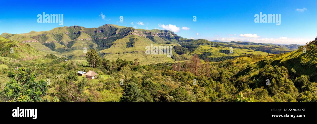 Panoramic view over a forest with a little hut embedded and green mountains, sunny day, Drakensberg, Giants Castle Game Reserve, South Africa Stock Photo
