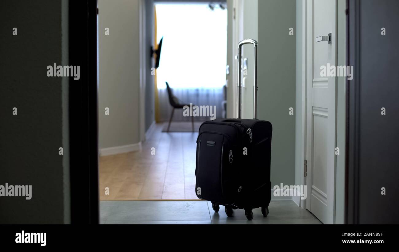 Door opened to room with suitcase in middle, check into hotel or check-out Stock Photo