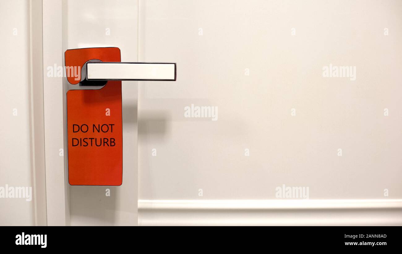 Red sign Do not disturb hanging on doorknob in hotel, privacy of hotel
