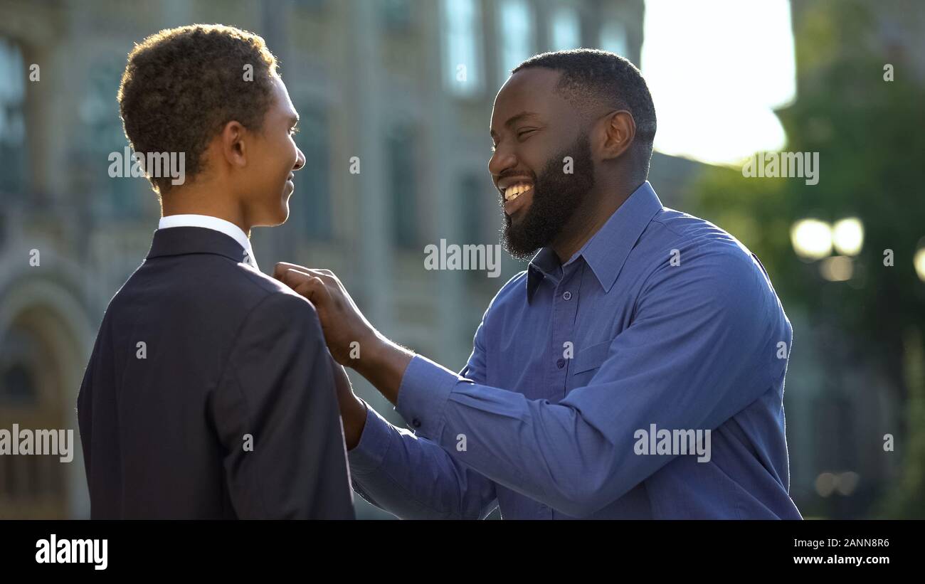 Excited african man feeling proud of young son in prom suit, college graduation Stock Photo