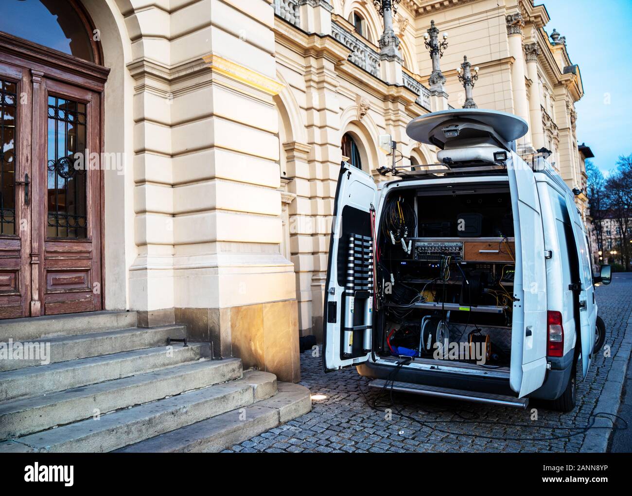 Television car in front of theatre transmitting spectacle live. Live scene  broadcast. Hidden electronic equipment at the cargo back. Stock Photo