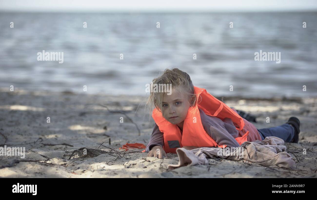 Little girl wearing life jacket lying on shore, survived plane crash