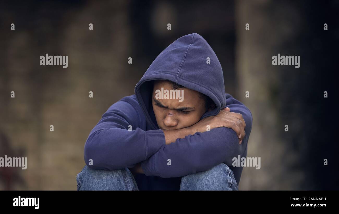 Desperate young man sitting street alone, domestic violence, running from home Stock Photo