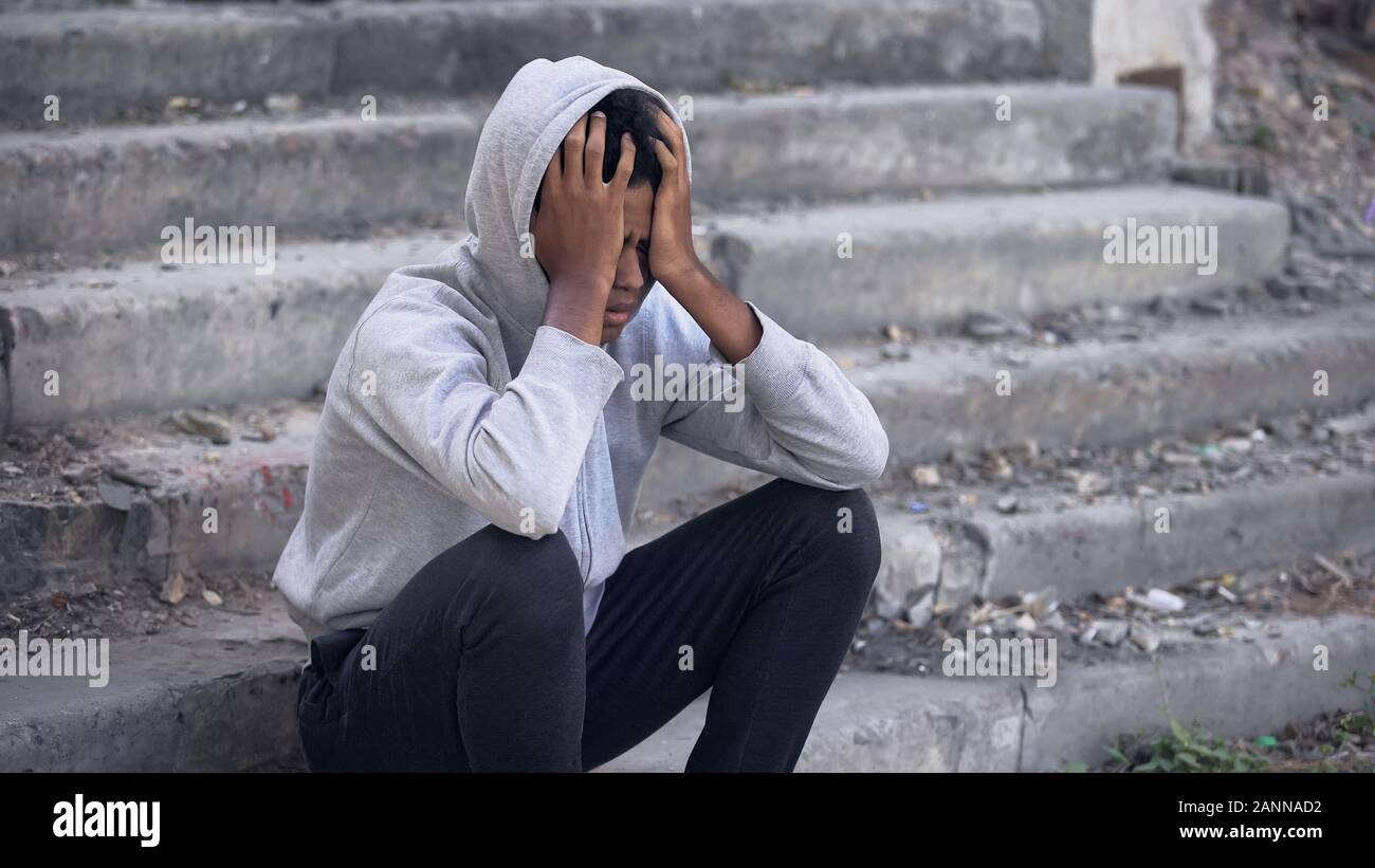 Depressed young black male sitting outside, emotional abuse, family problem Stock Photo