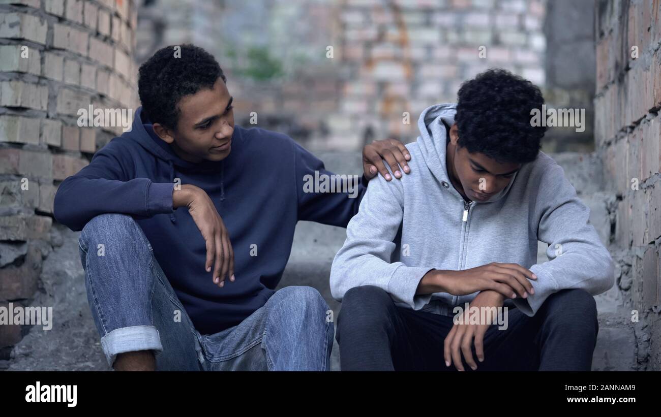 Afro-american teenager trying to make peace with friend, helping boy in need Stock Photo