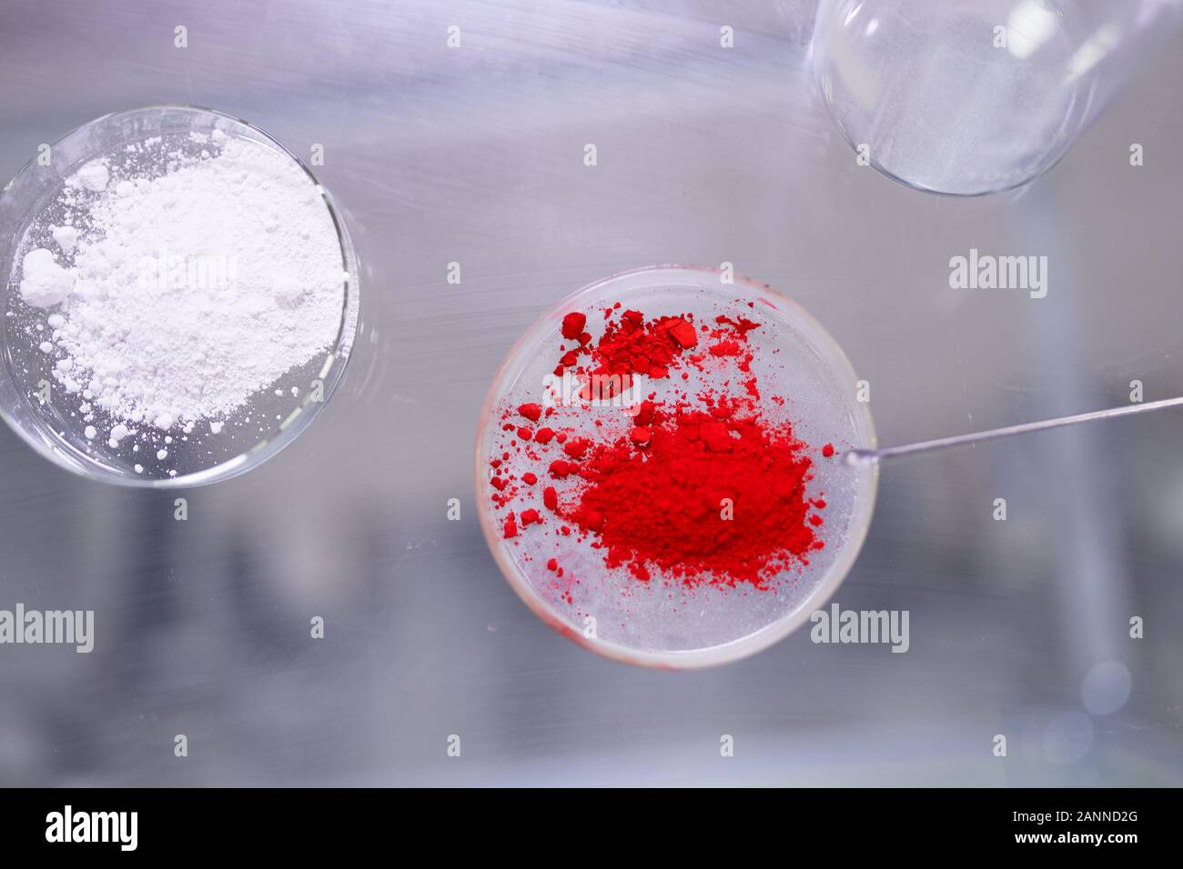 Two cups of petri dishes with red and white powder on table in