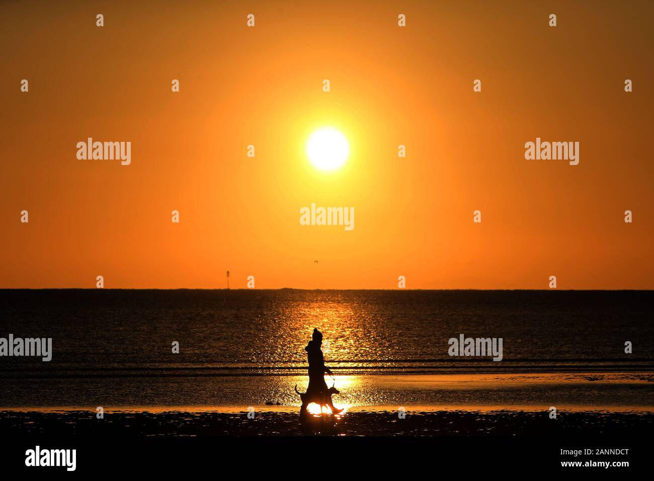 Ballywalter, County Down, Northern Ireland. 18th Jan, 2020. A woman walking her dog is silhouette as the sun rises on Millisle Beach in Ballywalter, County Down, Northern Ireland, Saturday Jan 18th, 2020. Freezing weather is expected across the UK/Ireland this weekend, with temperatures predicted to fall as low as -6C (21.2F). Credit: Paul McErlane/Alamy Live News Stock Photo