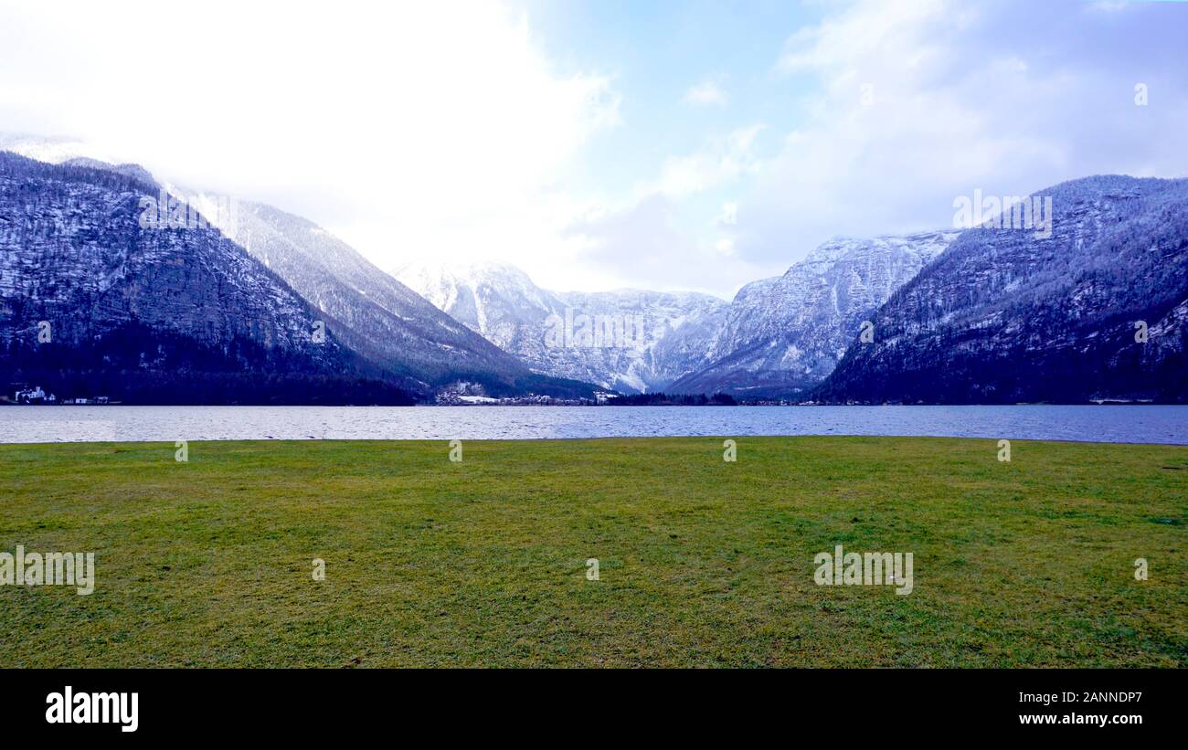 panorama of Hallstatt lake and green grass field outdoor dreamscape with snow mountain background in Austria in Austrian alps Stock Photo