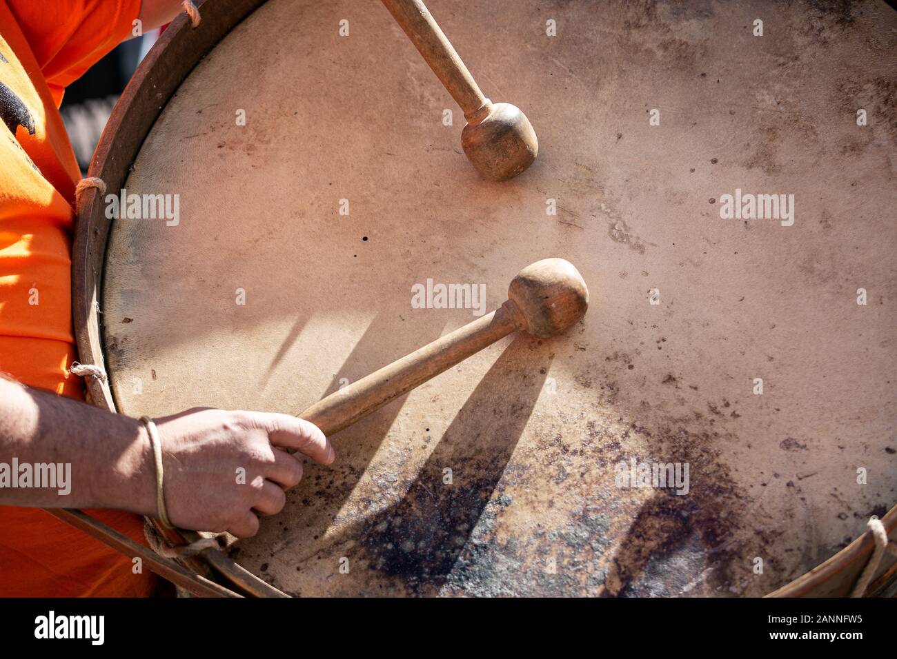 Musician hands with drum sticks playing a bass drum during an outdoor festival. Spanish culture Stock Photo
