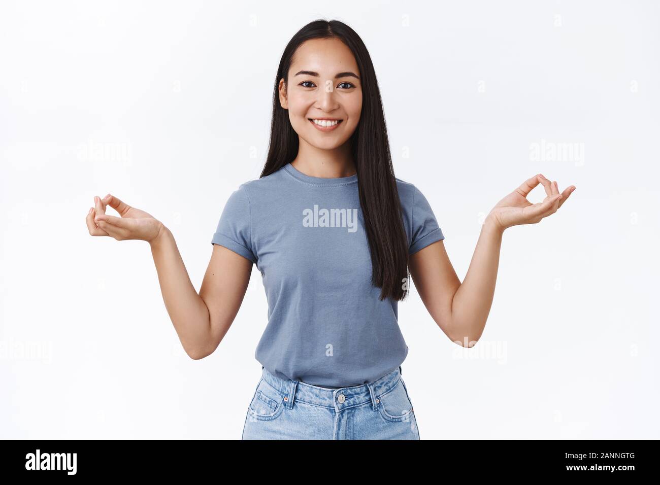 Happy, relaxed smiling asian girl finish meditation using smartphone app, open eyes and grinning relieved and joyful, feel boost of energy and positiv Stock Photo