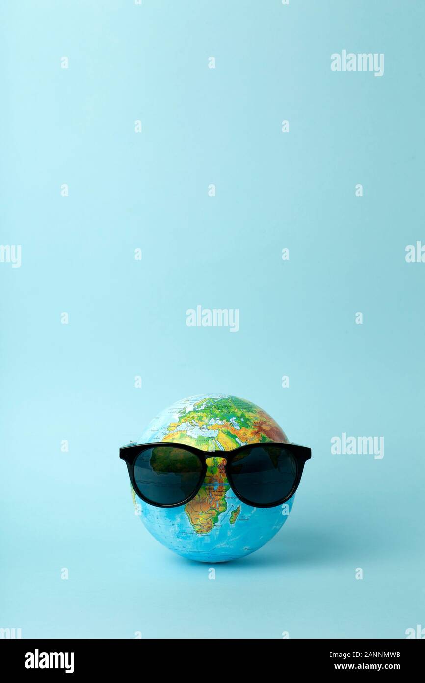 Tourism, ecology, vacation and globalism concept. Globe in sunglasses on a blue background banner. Minimal creative. Stock Photo