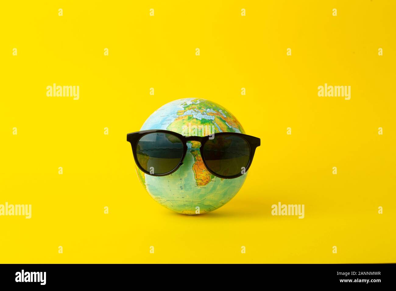 Tourism, ecology, vacation and globalism concept. Globe in sunglasses on a yellow background. Minimal creative. Stock Photo