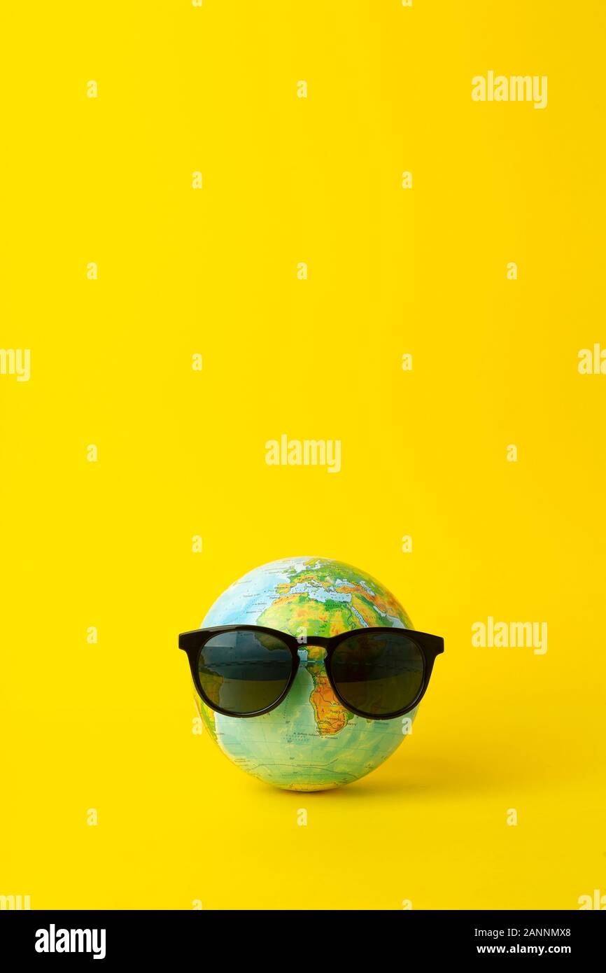 Tourism, ecology, vacation and globalism concept. Globe in sunglasses on a yellow background. Minimal creative. Stock Photo