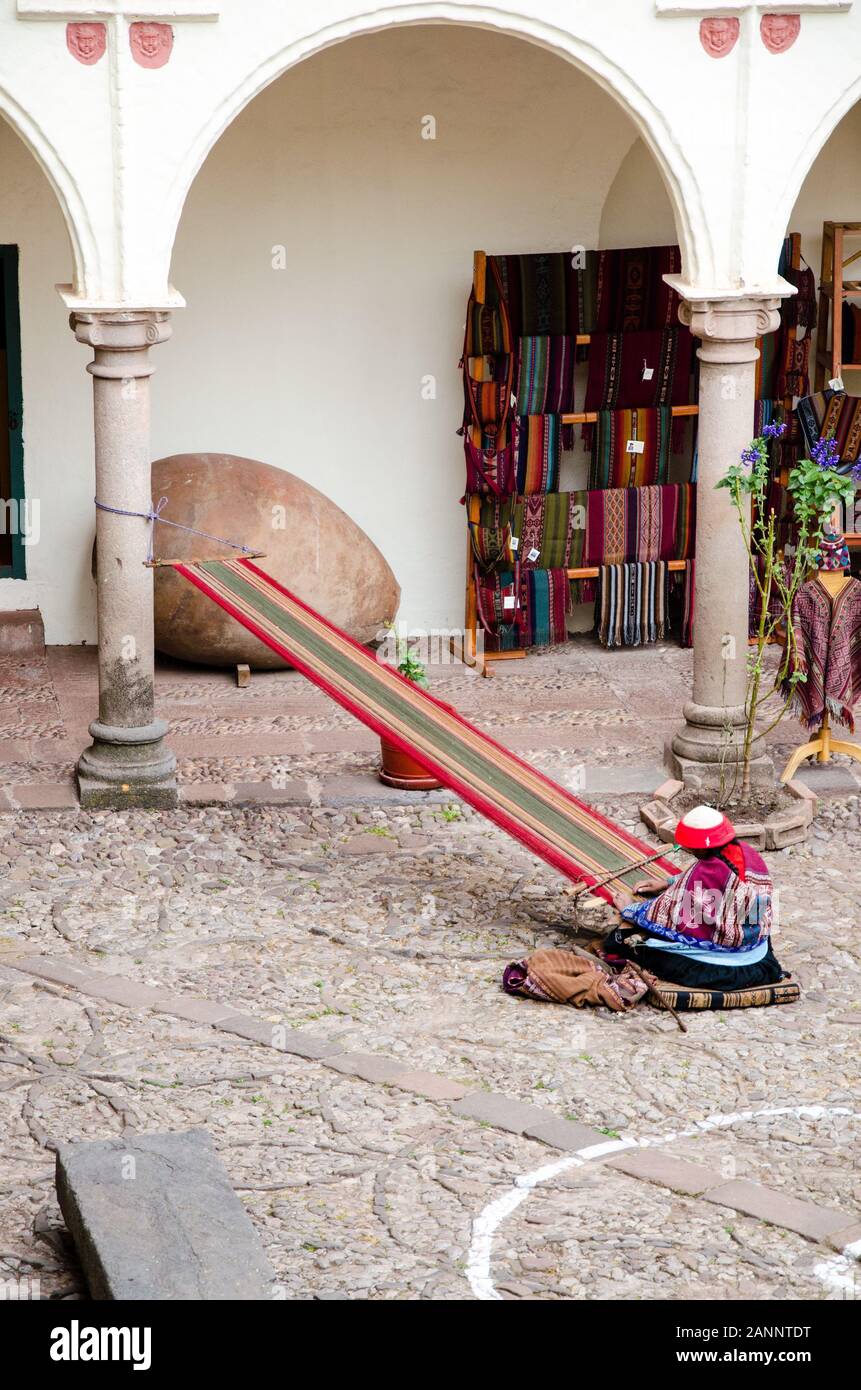 A indigenous peruvian woman is weaving alpaca wool to colourful fabrics in Cusco, Peru Stock Photo