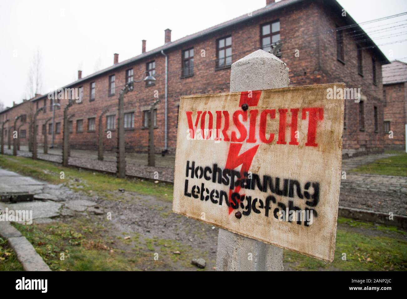 Vorsicht Hochsppannung Lebensgefahr sign (Caution, risk of electric shock sign) and barbed wire fence in Nazi German Konzentrationslager Auschwitz I S Stock Photo