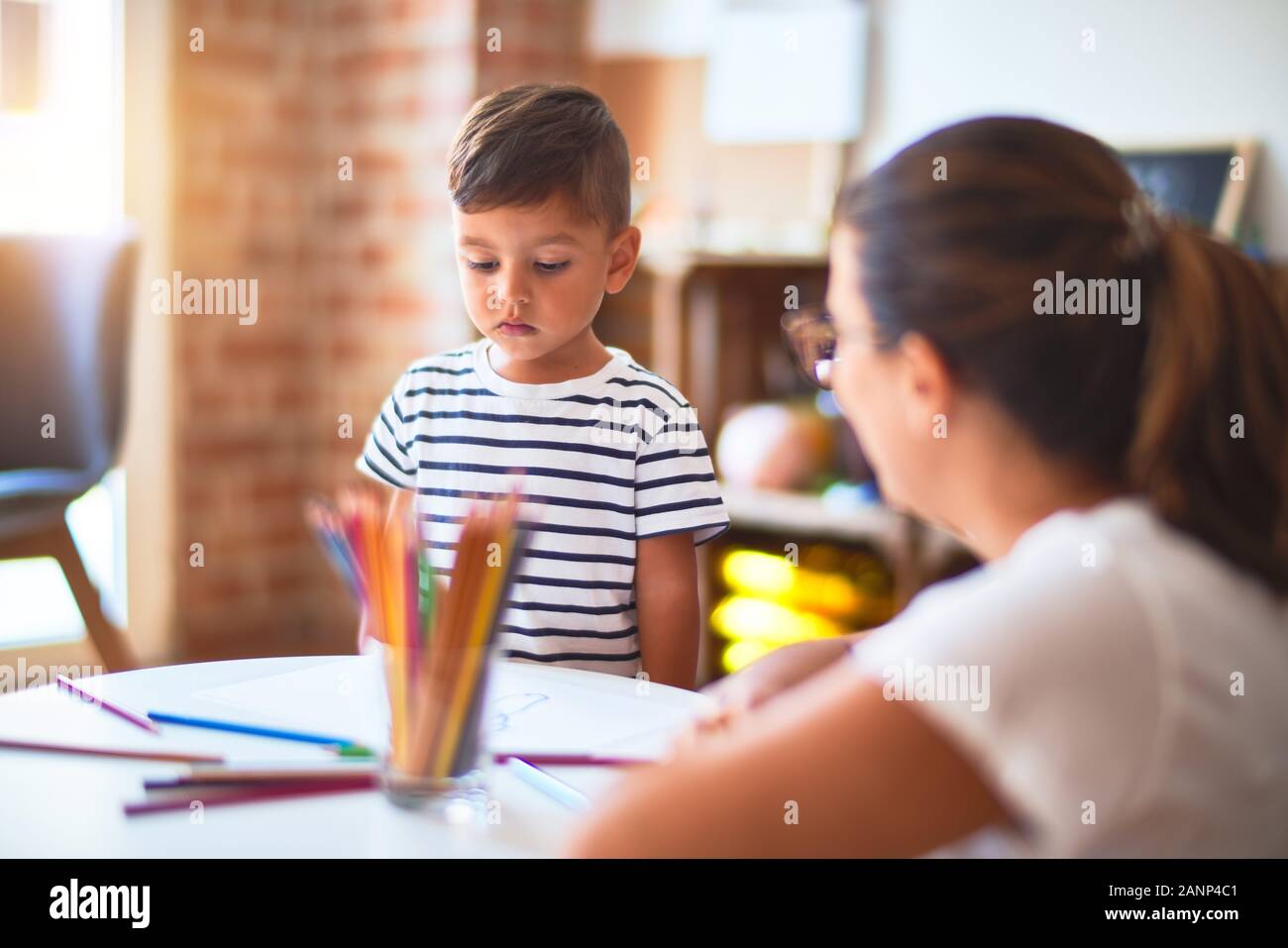 Beautiful teacher and toddler boy drawing draw using colored pencils at ...