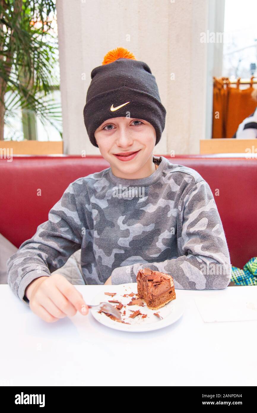 Boy eating chocolate cake at Palmenhaus Cafe Brasserie and Bar, Vienna, Austria, Europe. Stock Photo