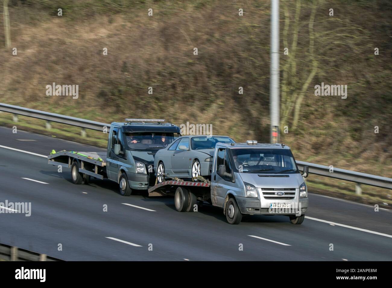 Ford Transit flatbed breakdown recovery truck driving on the M6 motorway near Preston in Lancashire, UK Stock Photo