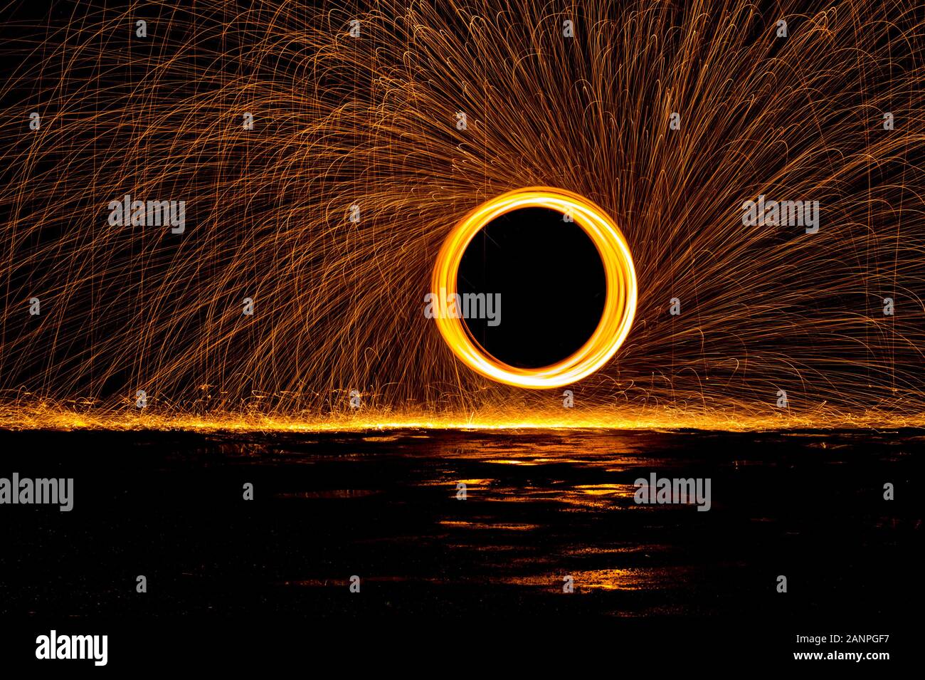 Steel wool painting with light in darkness spark effect and reflections on wet ground Stock Photo