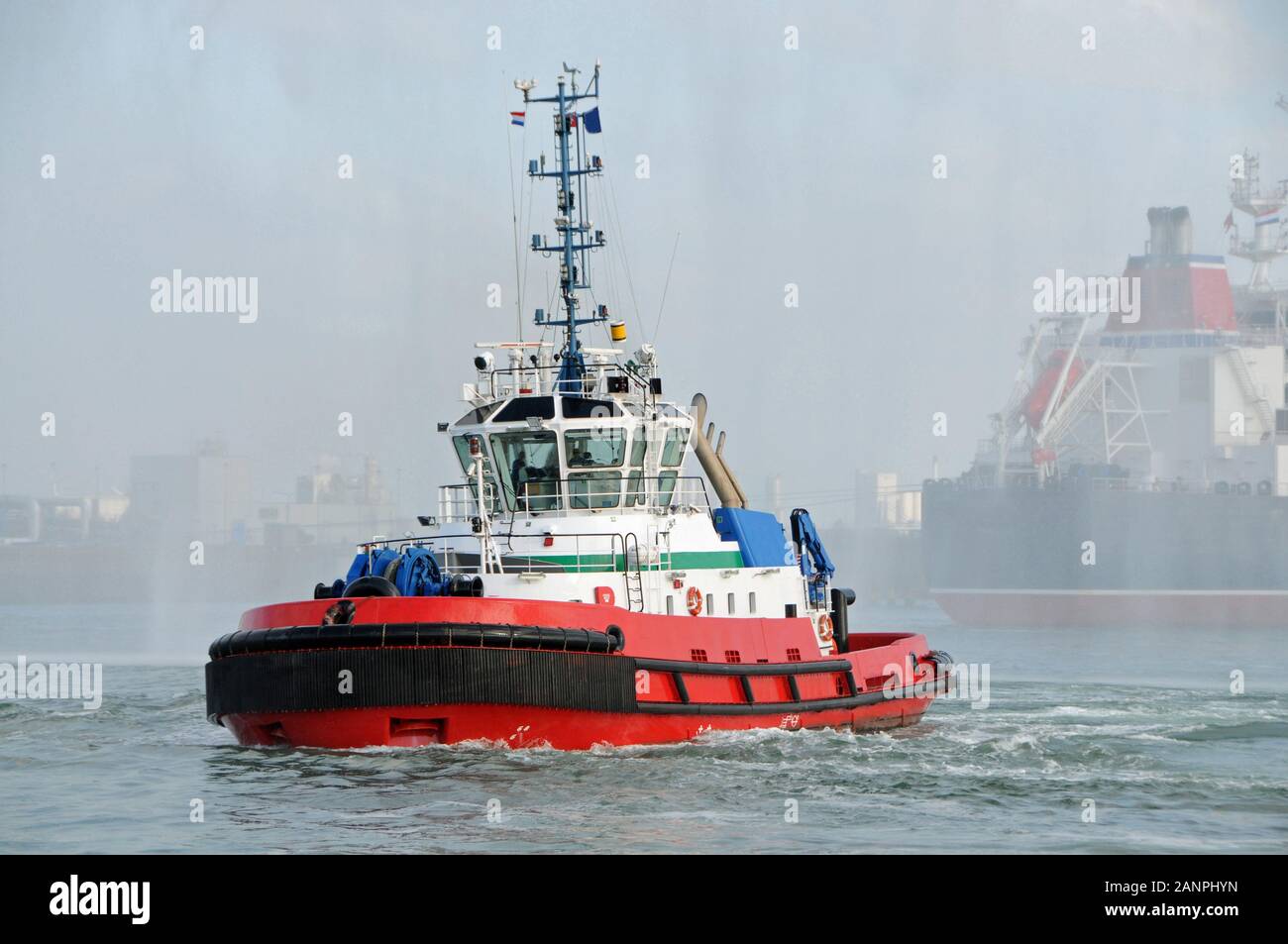 A tug on its way to an oiltanker in a foggy port of Rotterdam Stock Photo