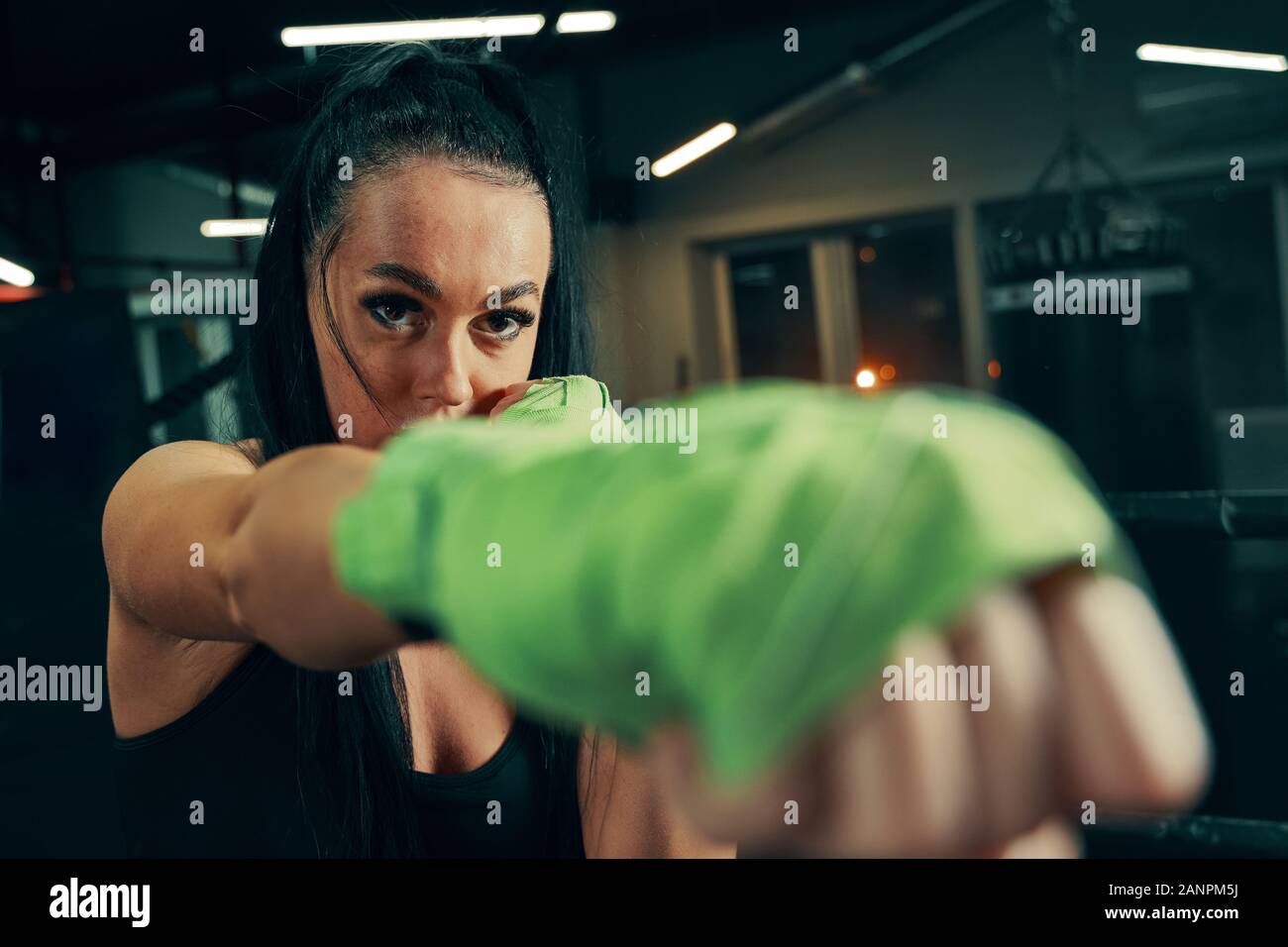 Athletic woman standing prepared for fight with boxing bandages on hands during box training Stock Photo