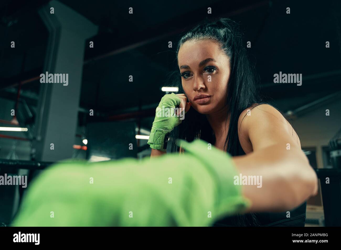 Athletic woman standing prepared for fight with boxing bandages on hands during box training Stock Photo