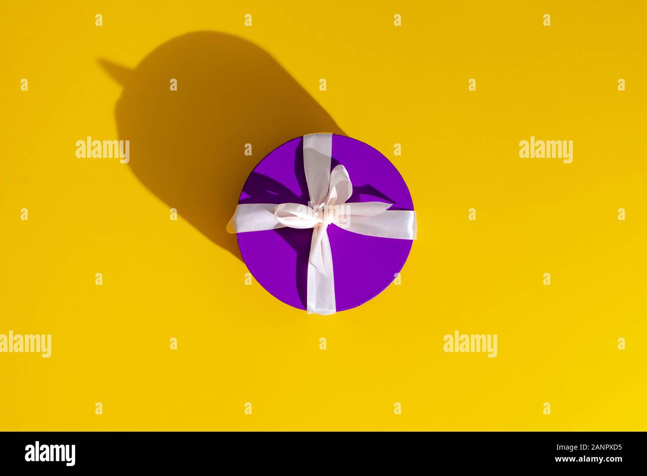 a violet gift box on yellow background. Stock Photo