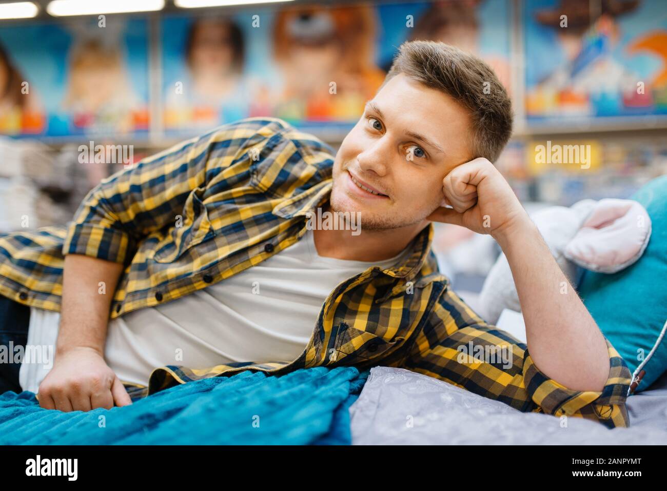 Young man lying on the bed in bedding store Stock Photo