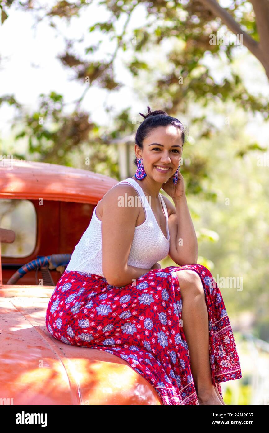 Cute latin woman posing on an orange car Stock Photo