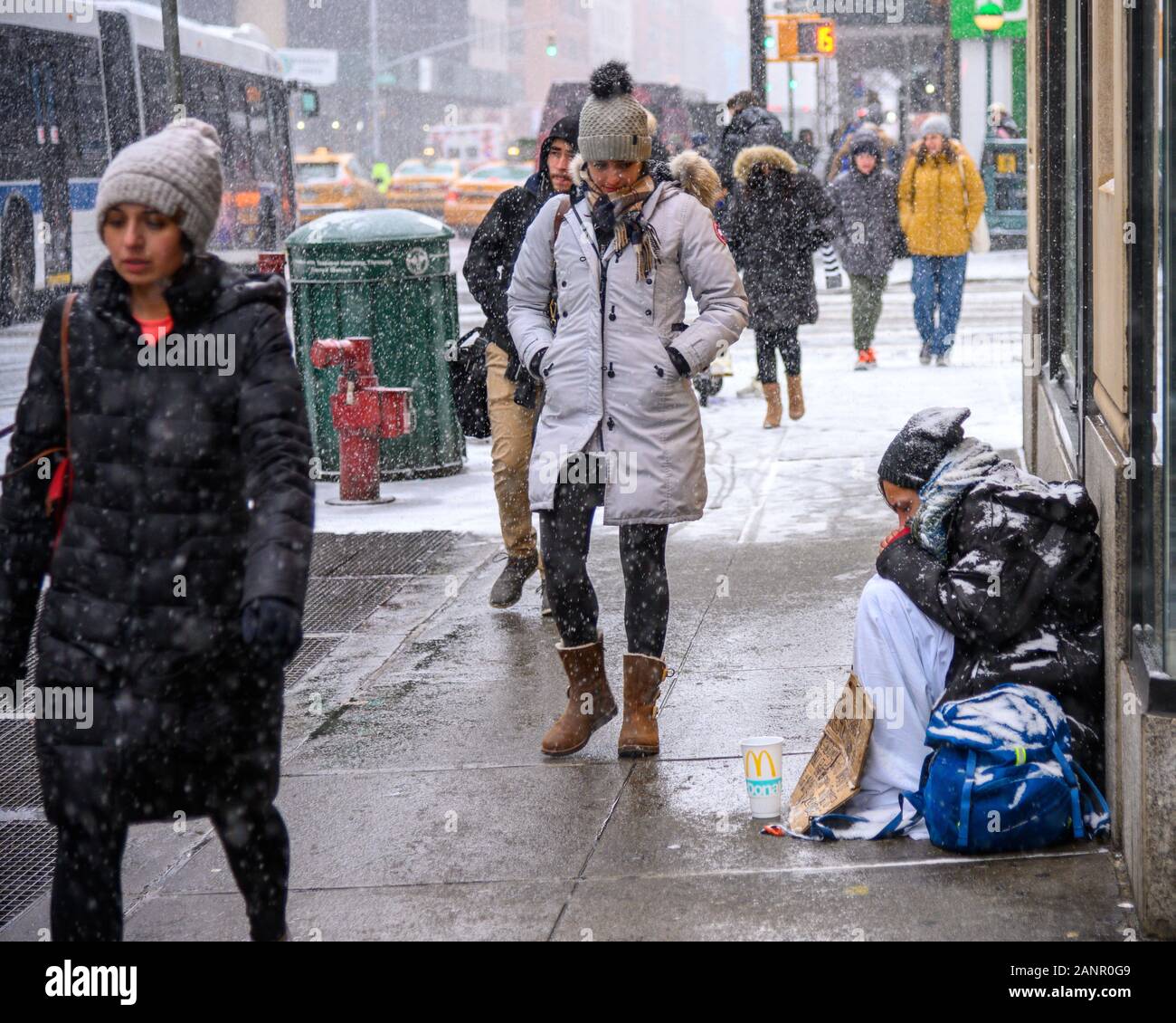 New York, USA,  18 January 2020. Passers-by walk past a homeless man in New York City's Upper East Side during a snowstorm.   Credit: Enrique Shore/Alamy Live News Stock Photo