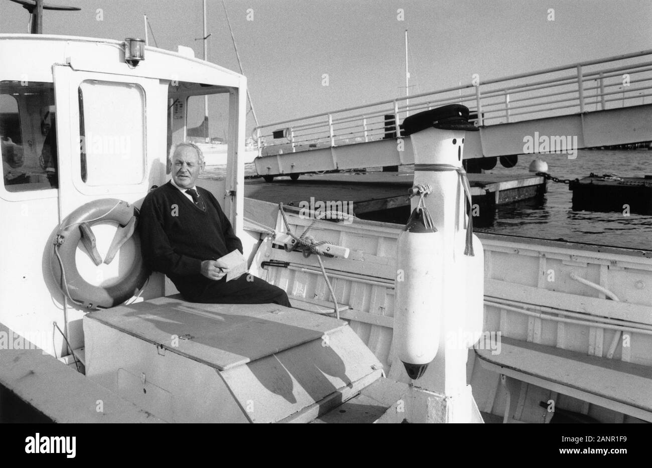 Skipper of the Gosport Boatyard water taxi poses on board: Hardway, Gosport, Hampshire, England, UK.  Black and white film photograph.  MODEL RELEASED Stock Photo