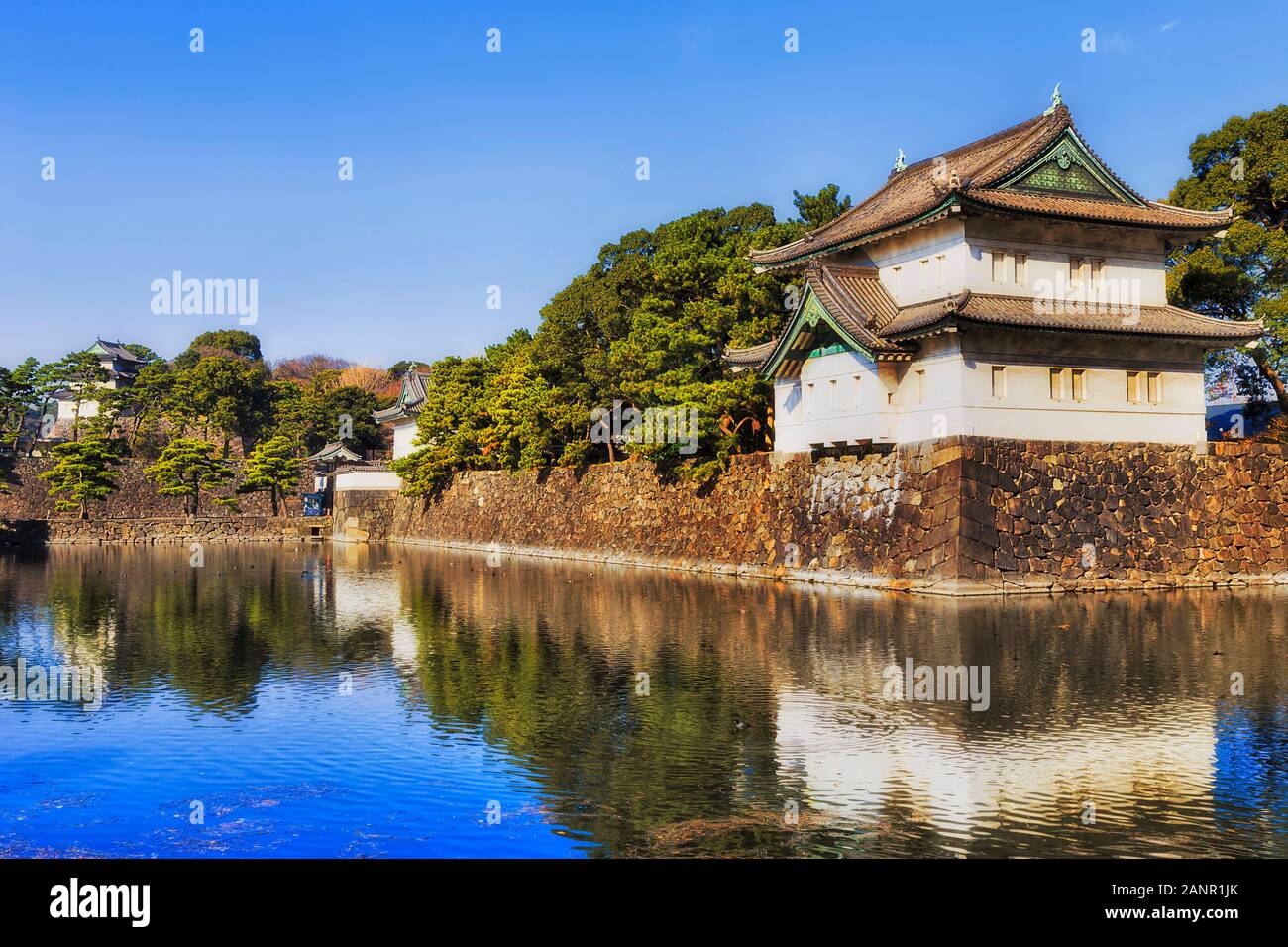 The imperial palace and Eastern garden in Tokyo, Japan. White corner tower on top of stone wall reflecting in water moat. Stock Photo