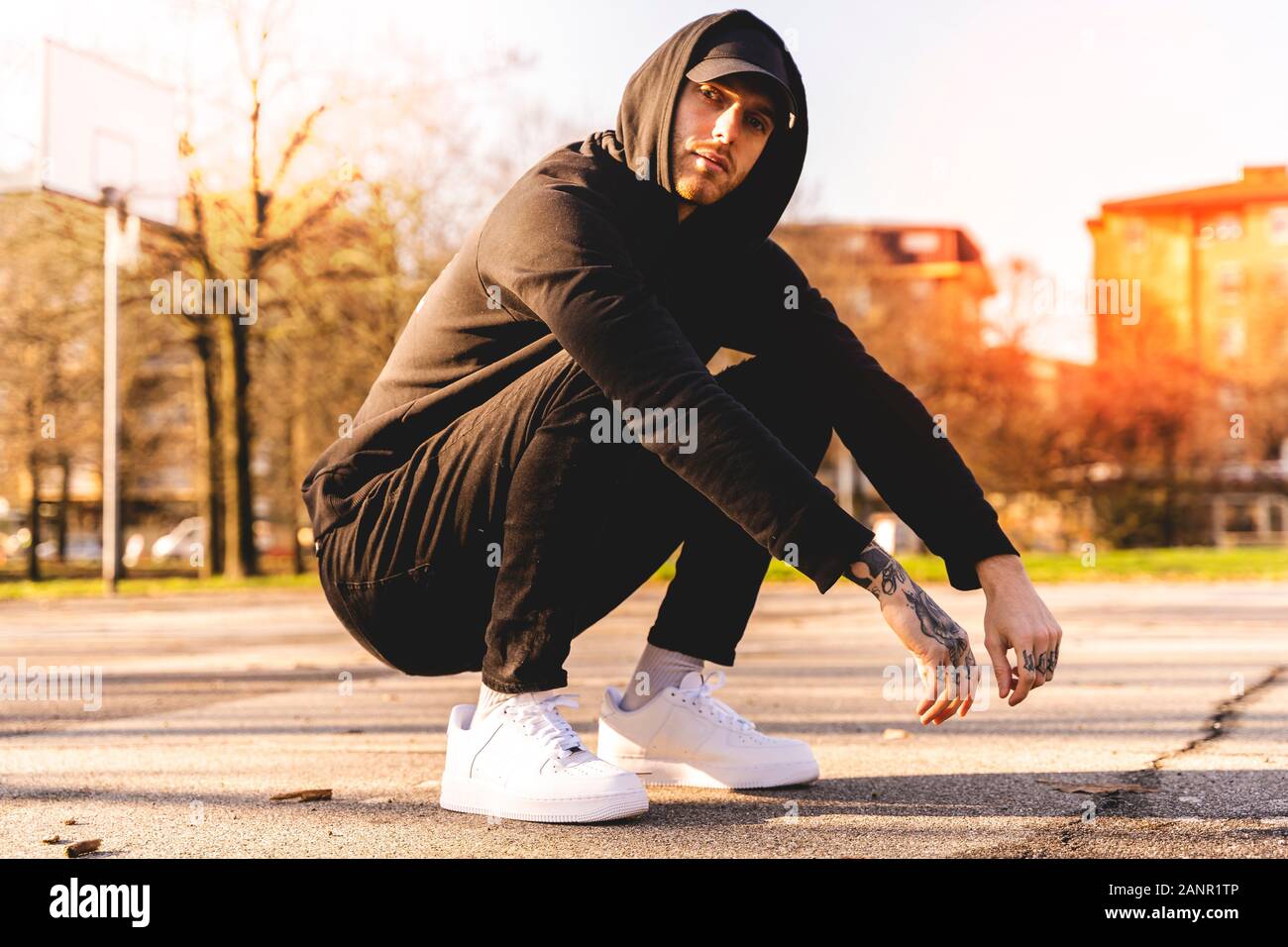portrait of young rapper posing in the middle of an outdoor basketball  court on the outskirts Stock Photo - Alamy