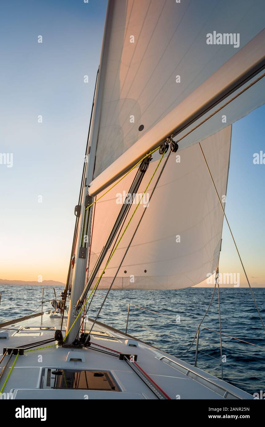 Chasing the sun at sailing yacht. Deck and sails of sailoat pointing to the  sunrise. Mediterranean sea, Italy Stock Photo - Alamy