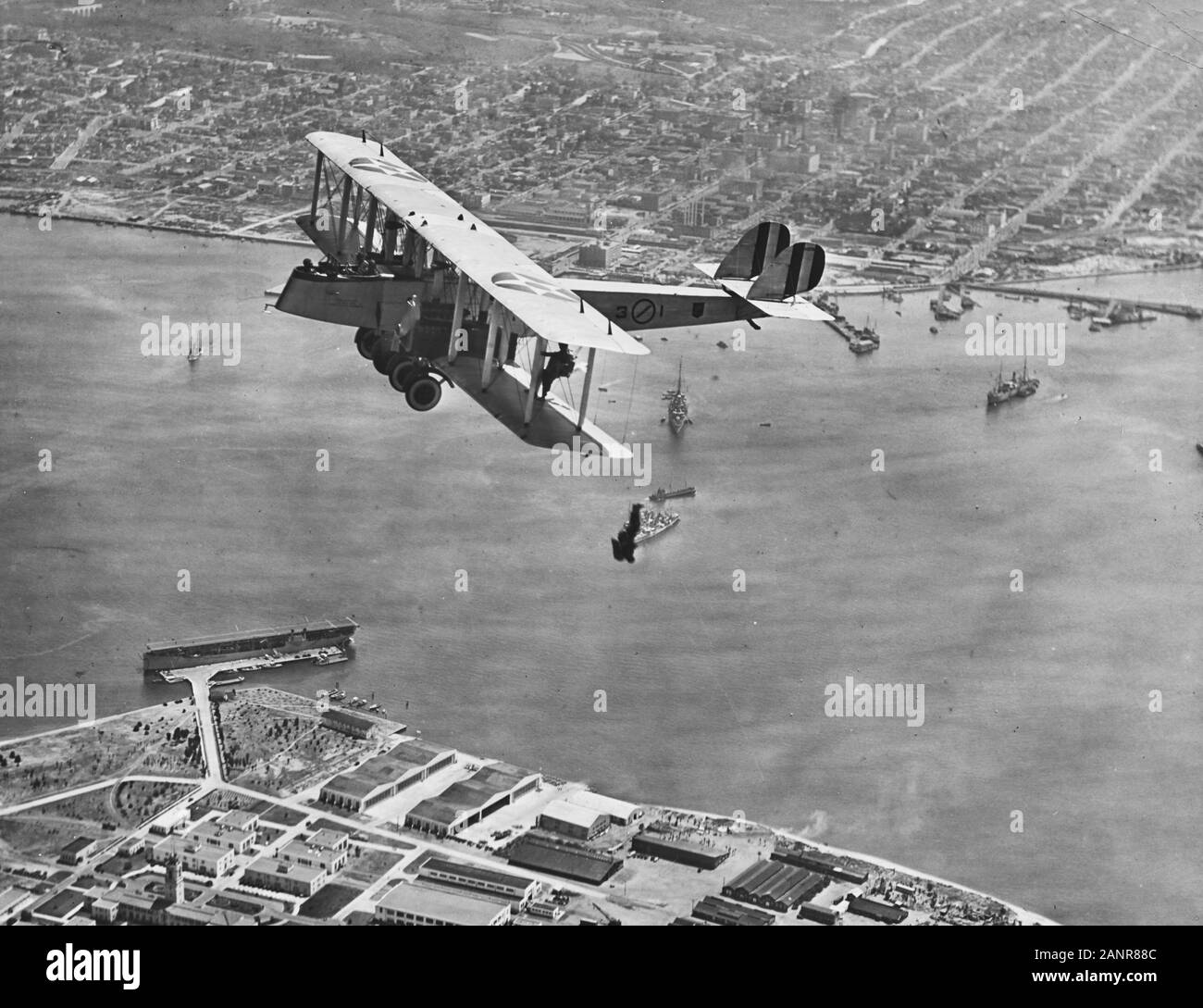 Martin MT bomber Dropping parachutists over Naval Air Station North Island, San Diego, California, during the early 1920s. One of these men is AMM2 T.D. Ferguson. Note USS Langley (CV-1) docked below. Stock Photo