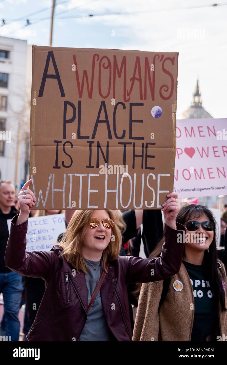 San Francisco, USA. 18th January, 2020. The 4th annual Women's March San Francisco, California. A woman holds a sign reading, 'A woman's place is in the White House,' as protesters march down Market Street (vertical format). Stock Photo