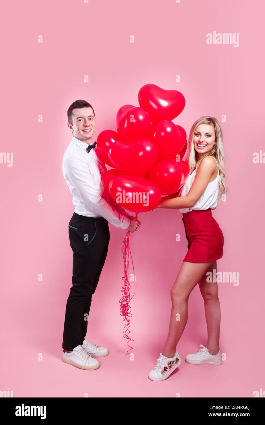 Happy couple posing on pink background with balloons heart. Valentine's ...