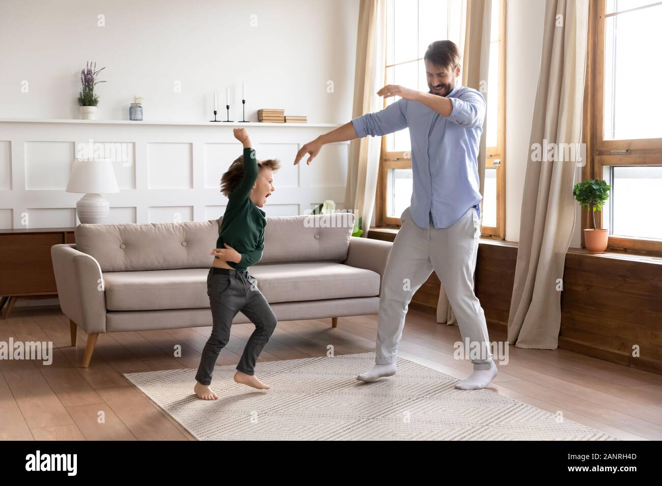 Happy young dad dancing jumping with little son Stock Photo