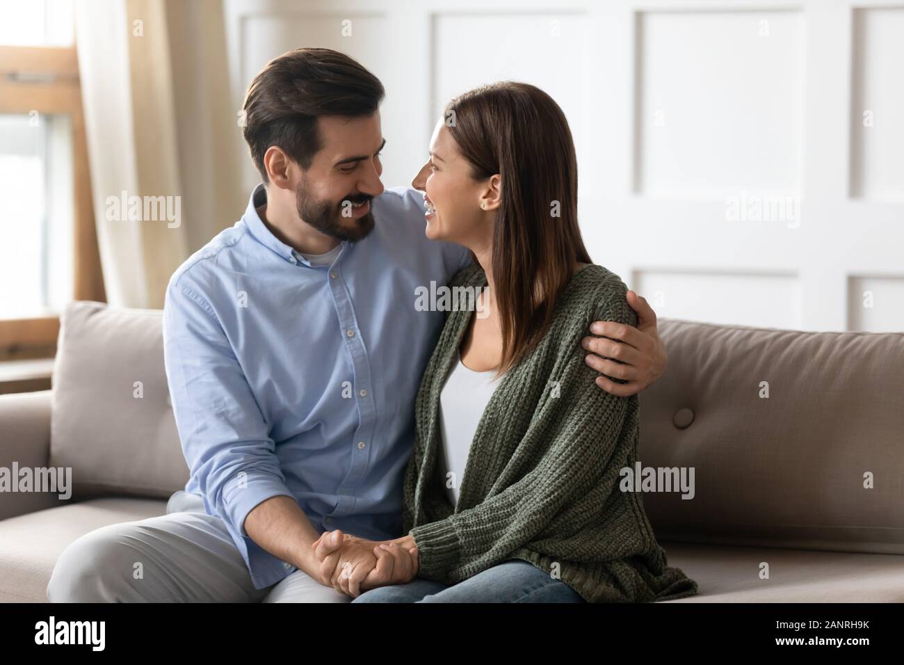 Happy couple sit on couch hugging reunited after fight Stock Photo - Alamy